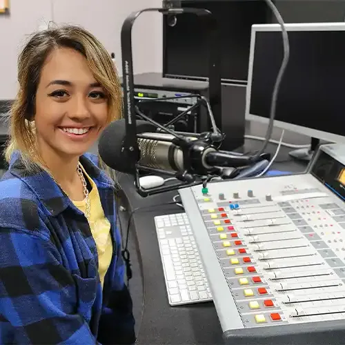 image of a student sitting in a radio broadcast booth